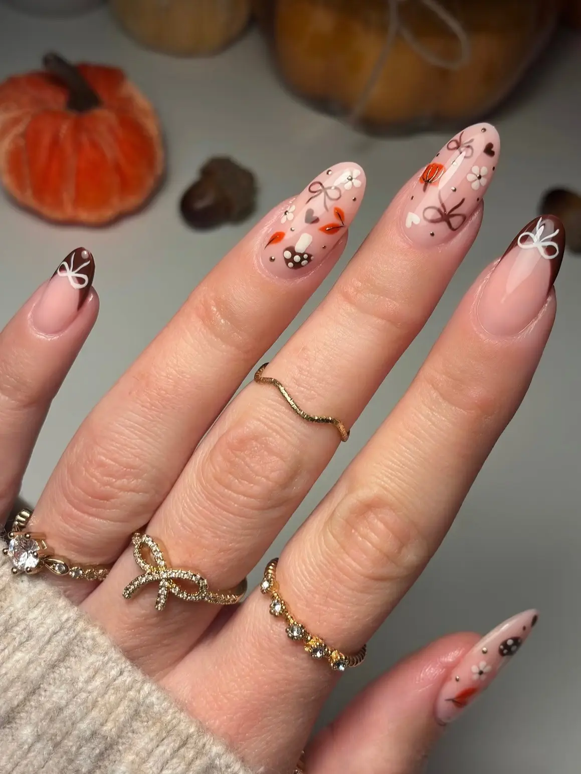 Sheer pink almond nails with brown bow French tips and hand-painted mushrooms, autumn leaves and flowers