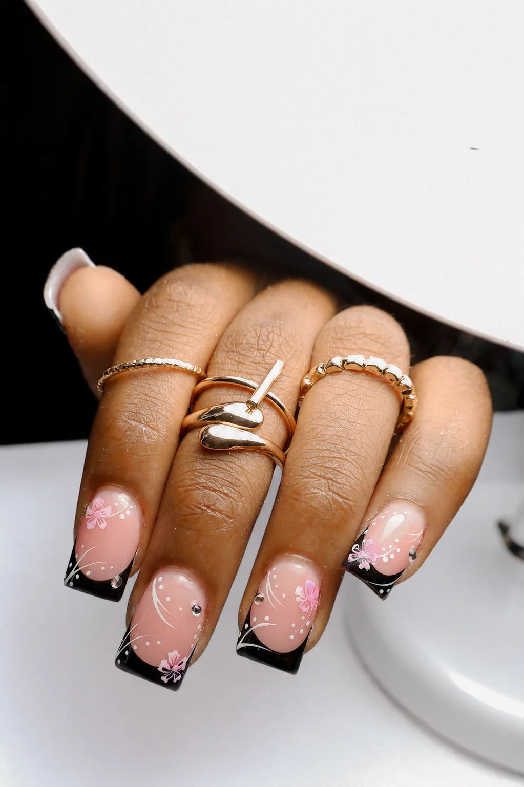Short square nails with black French tips and pink cherry-blossom accents