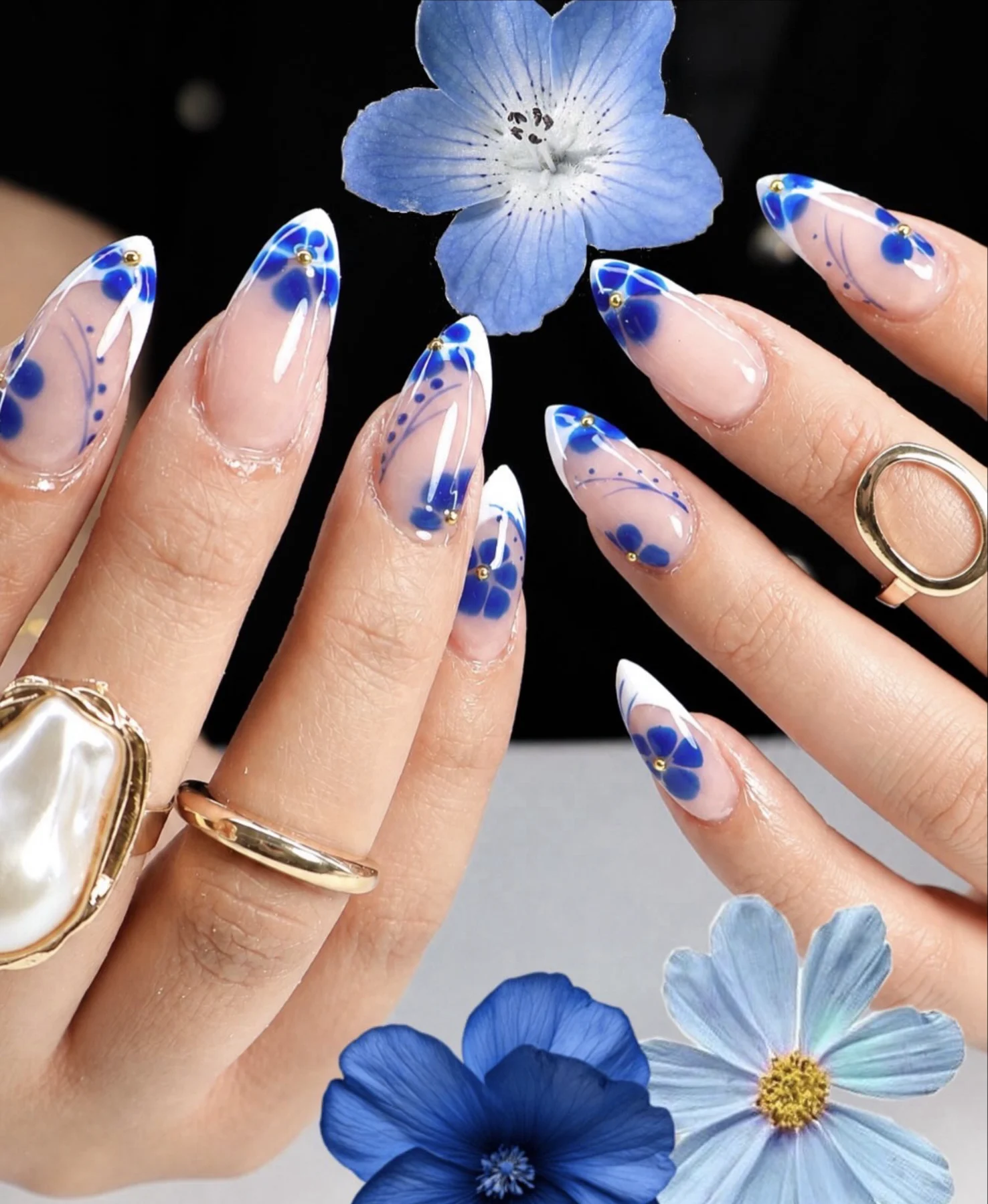 Sheer almond nails with hand-painted blue flowers and white French edges