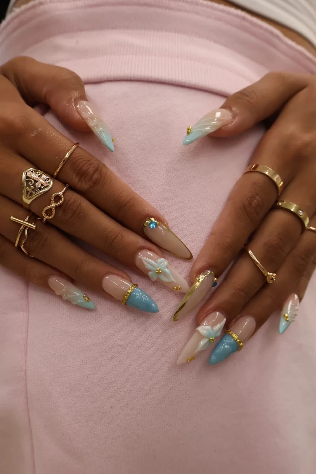 Both hands showing blue and nude stiletto nails with 3D flower nail art