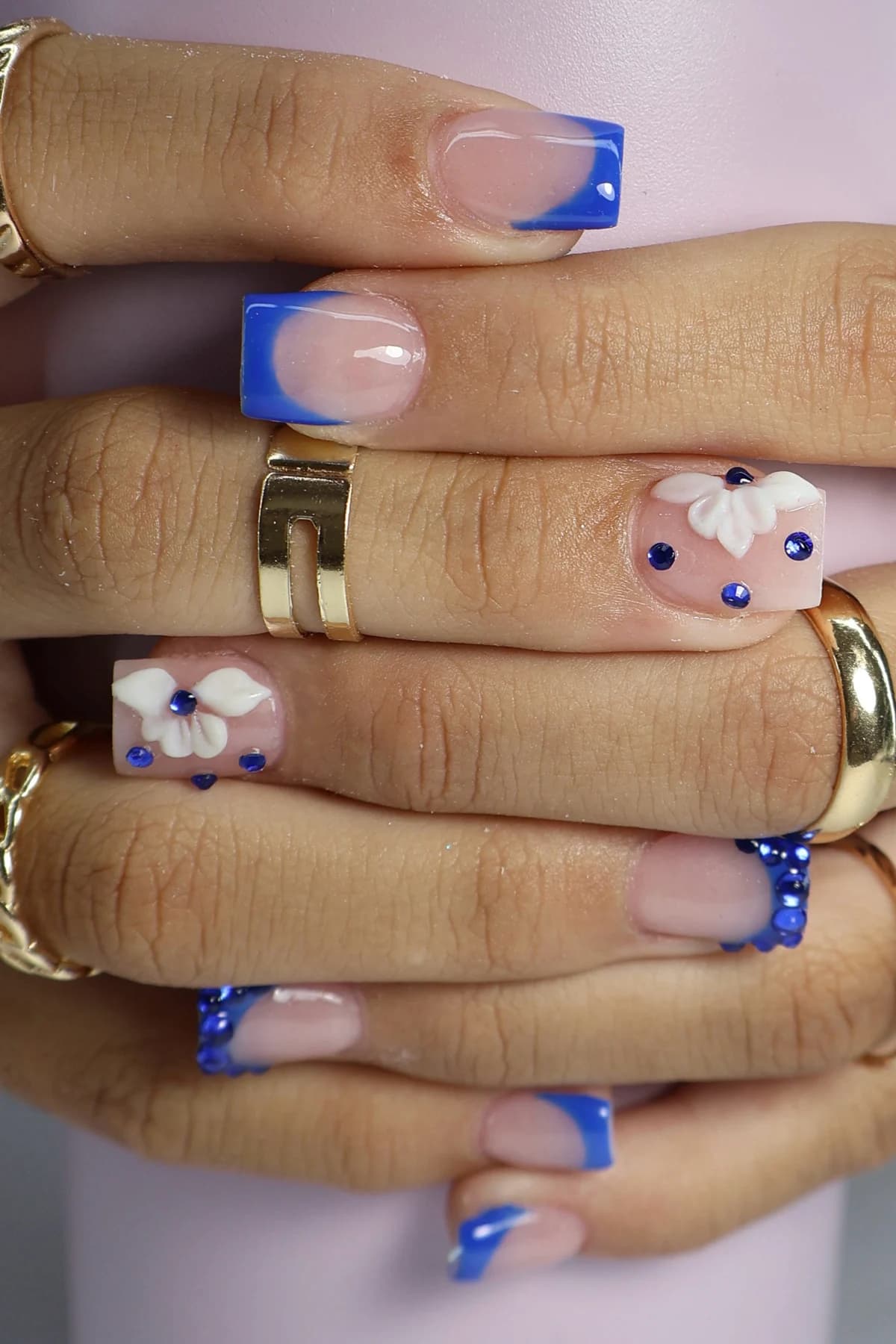 Royal-blue French tip nails with white 3D flowers and blue rhinestones