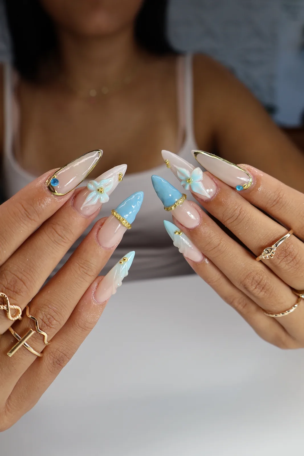 Sheer blue jelly stiletto nails with 3D white flowers and gold chrome accents