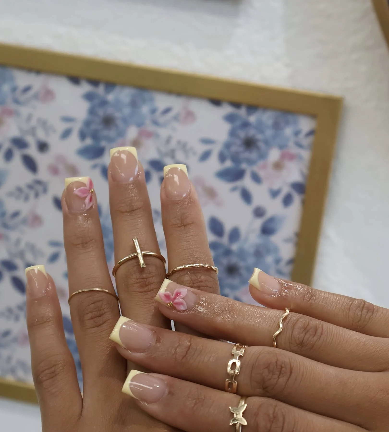 Butter-yellow micro French nails with a small pink flower accent