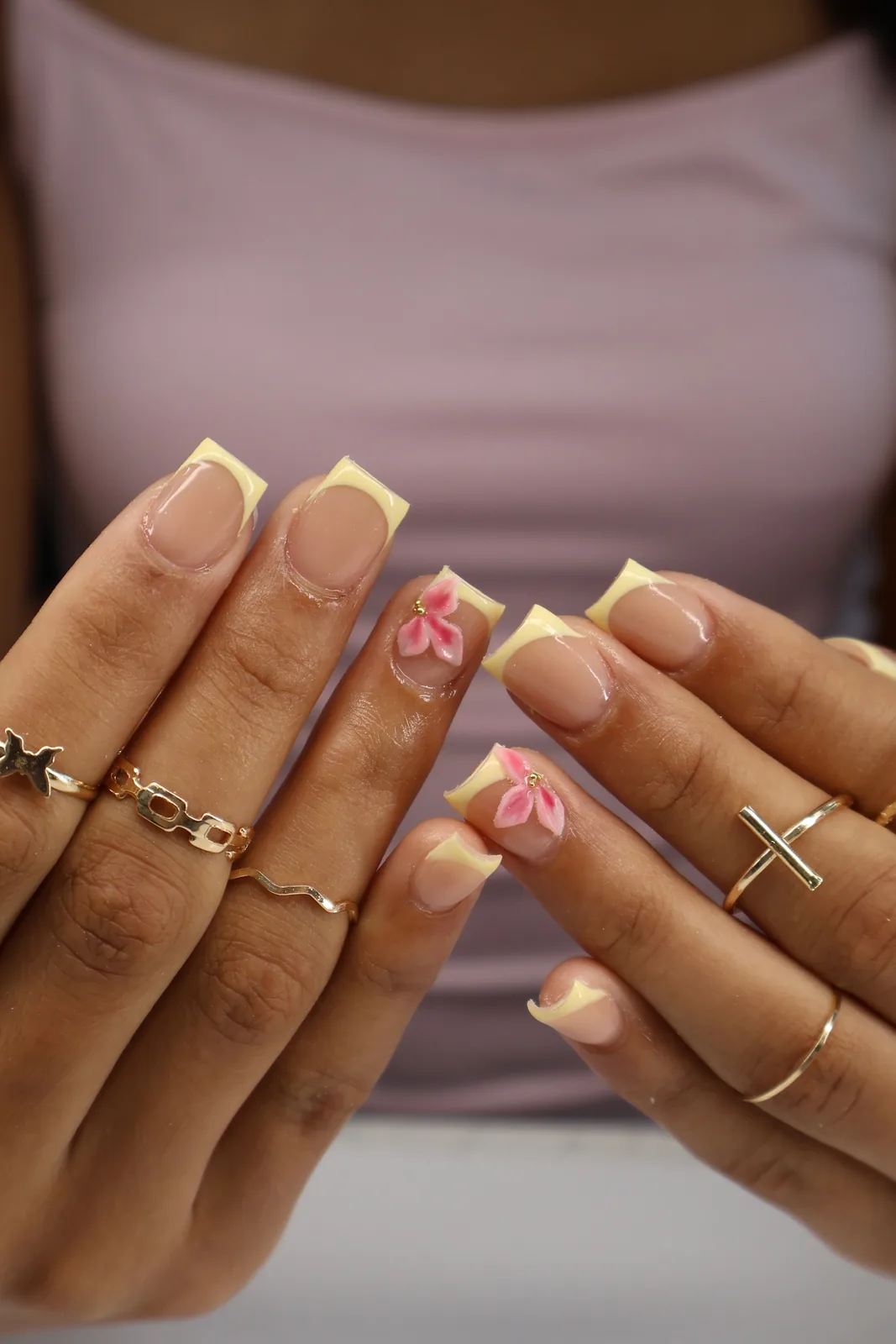 Pale yellow French tips with hand-painted pink lily accents