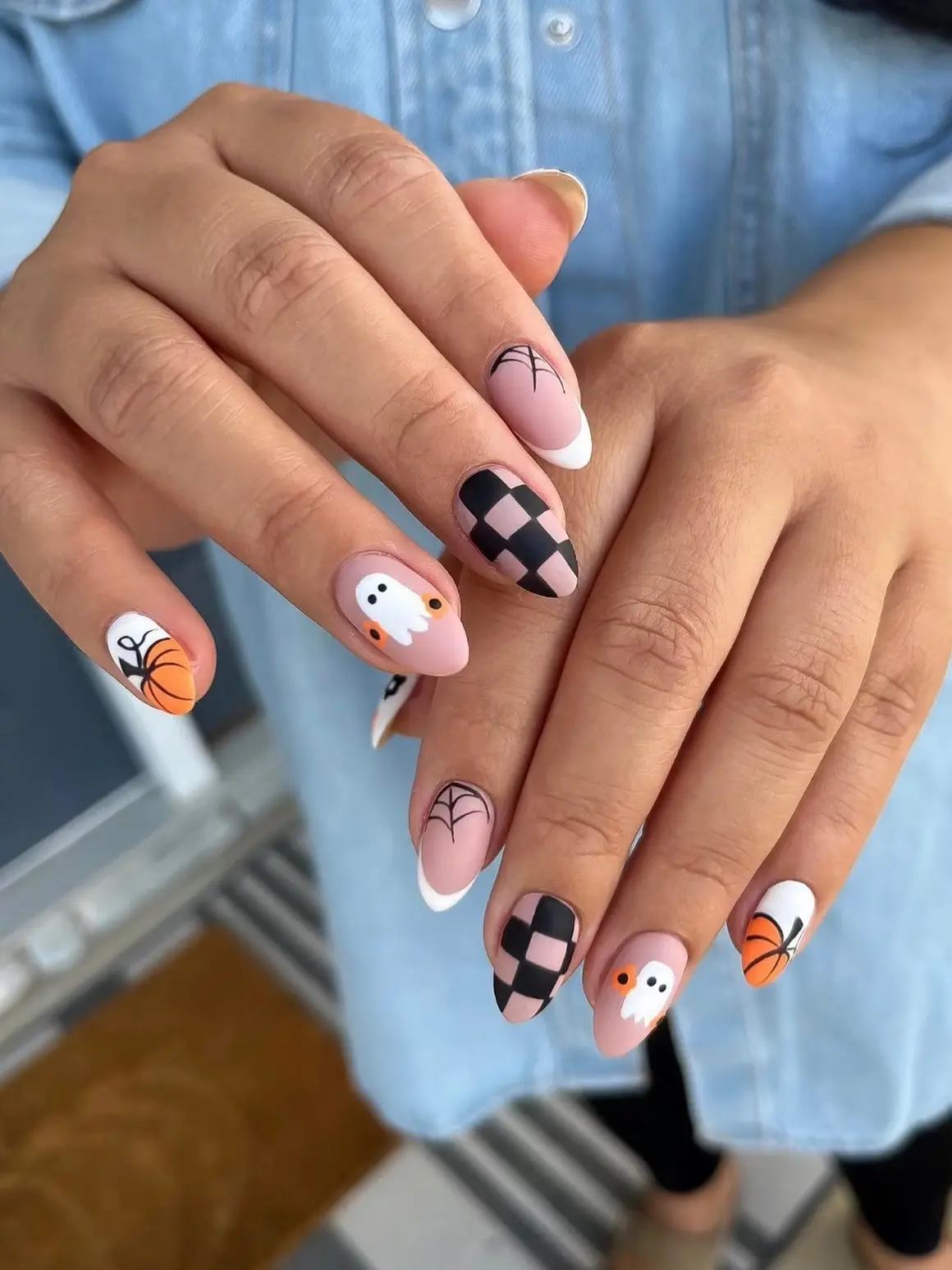 Almond Halloween nails with black and nude checkerboard, ghosts, pumpkins and cobweb French tips