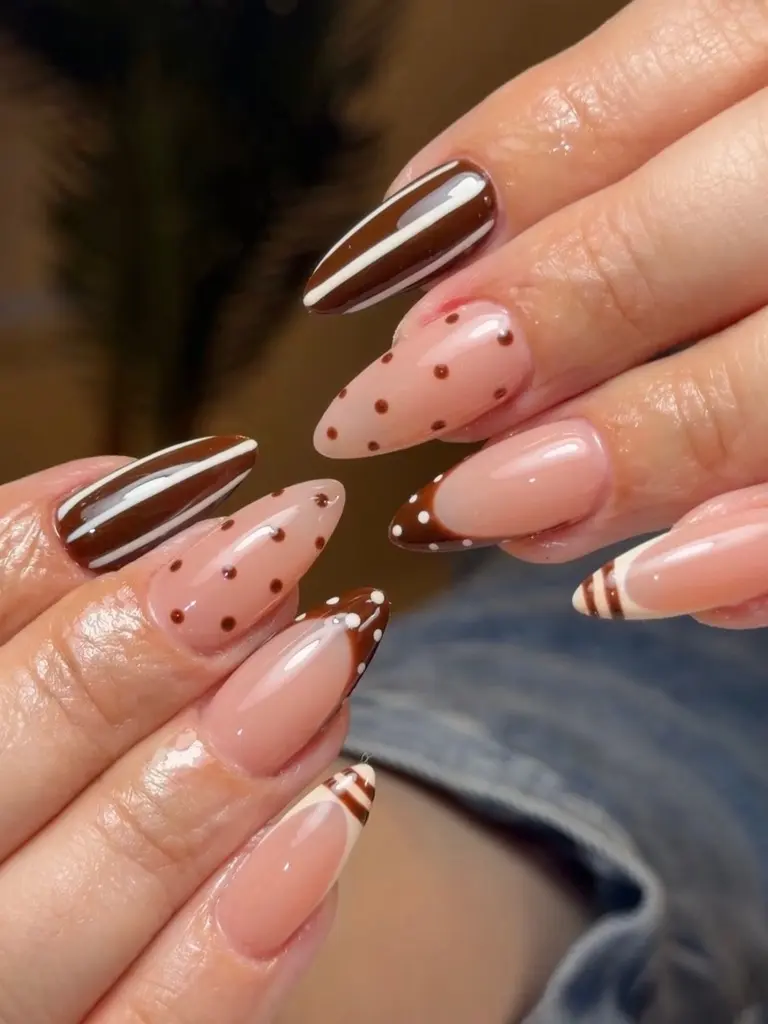 Almond nails mixing glossy chocolate brown with cream stripes, brown polka dots on nude, and dotted brown and striped cream French tips