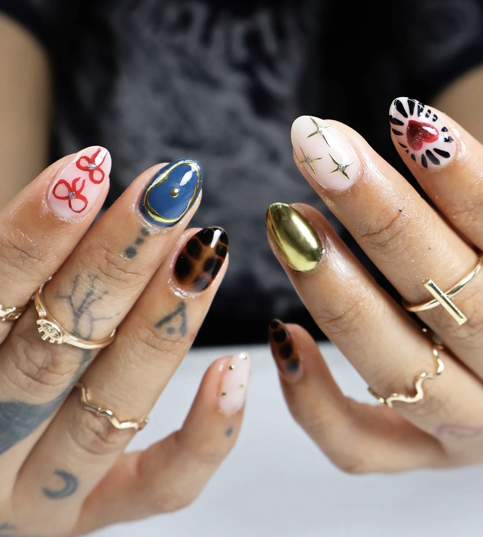 Eclectic almond nail art mixing gold chrome, navy, tortoiseshell, and hearts
