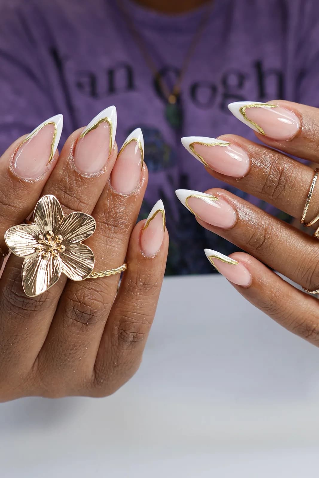 White French stiletto nails outlined in gold, created at King & Queen Nails & Spa