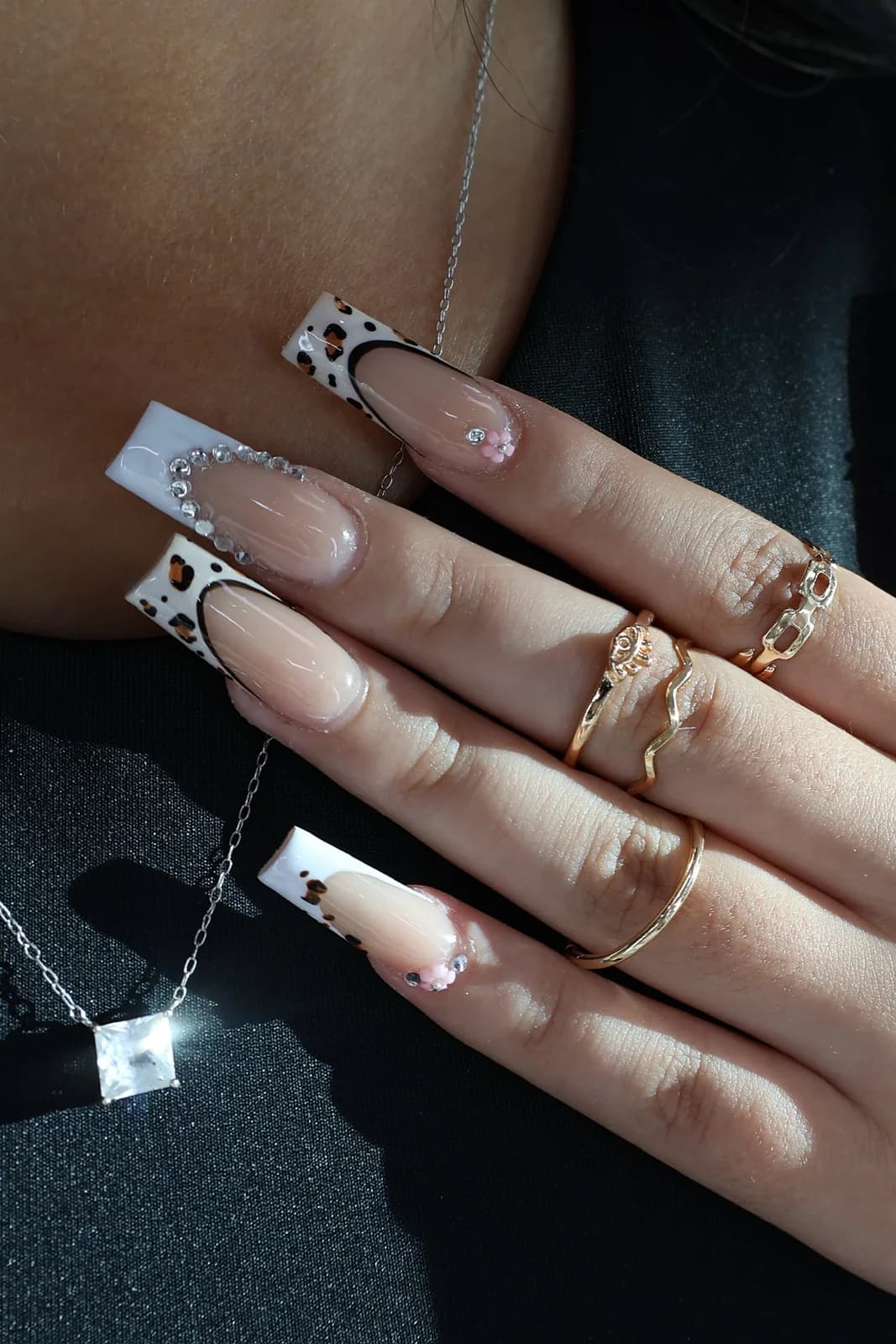 Leopard print French nails with crystals, worn with a silver pendant necklace