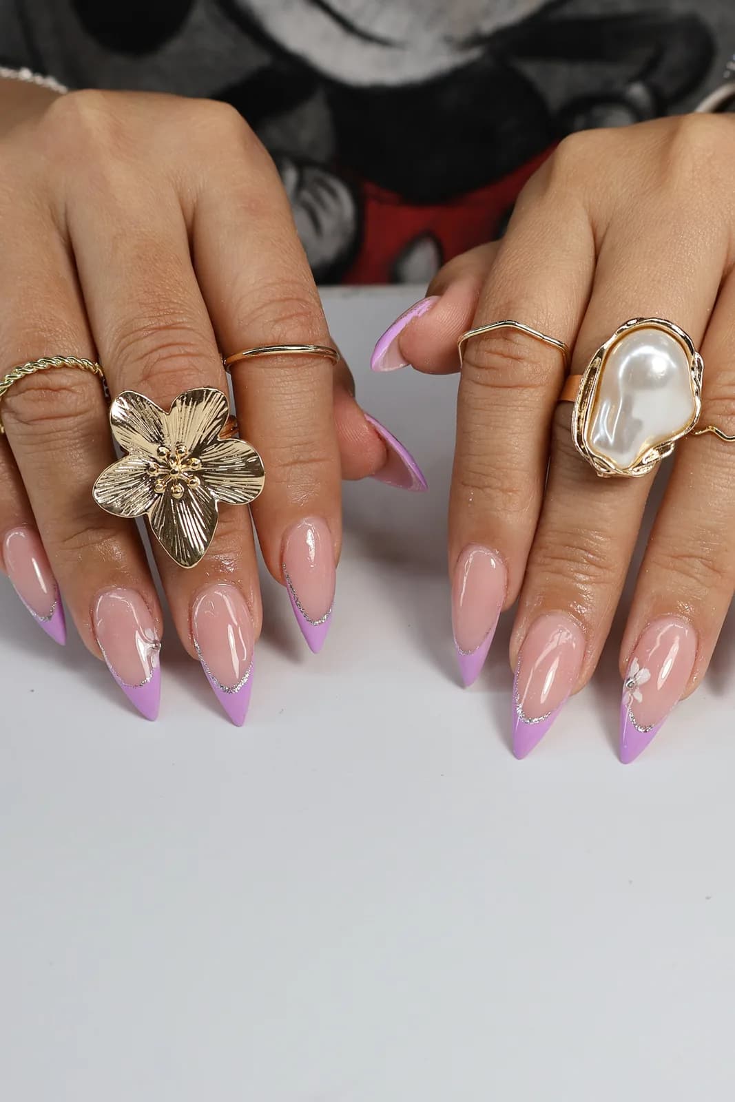 Both hands showing lilac purple French tips on sharp stiletto nails
