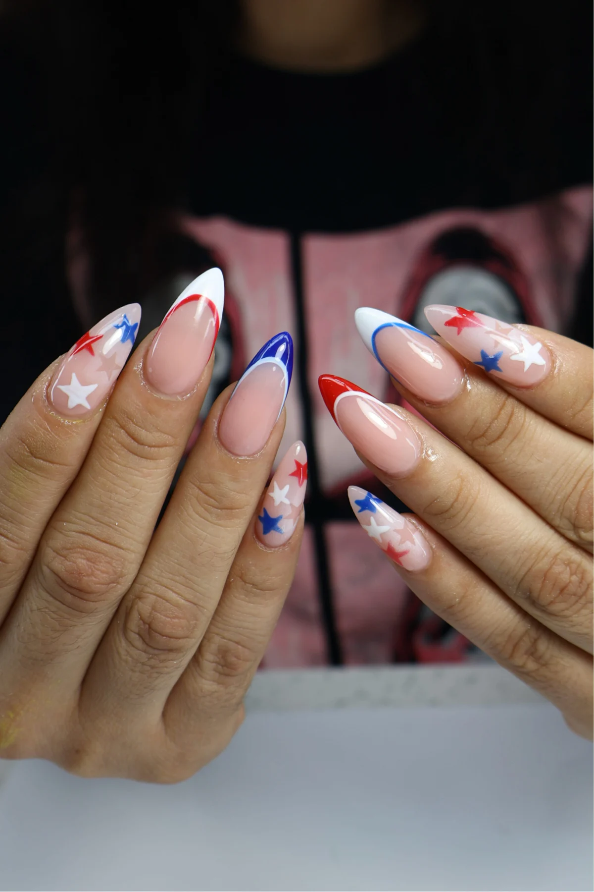 Sheer almond nails with red and blue French tips and star accents