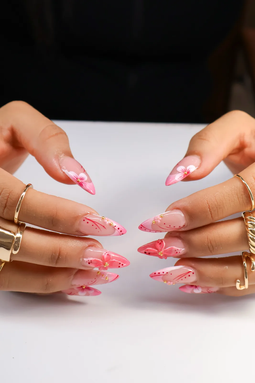 Both hands showing pink butterfly nail art on pointed almond nails