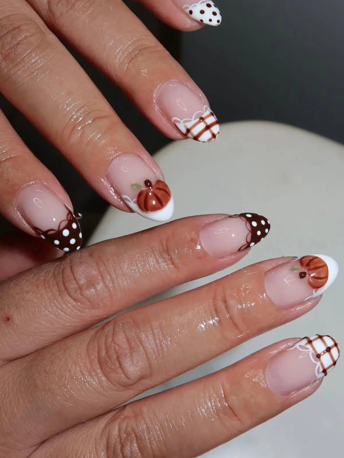Both hands with pumpkin, plaid and brown polka-dot French tip fall nails
