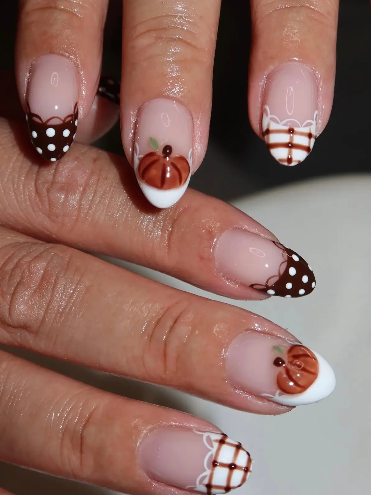 Almond fall nails with chocolate polka-dot French tips, a pumpkin on white French and a plaid tip