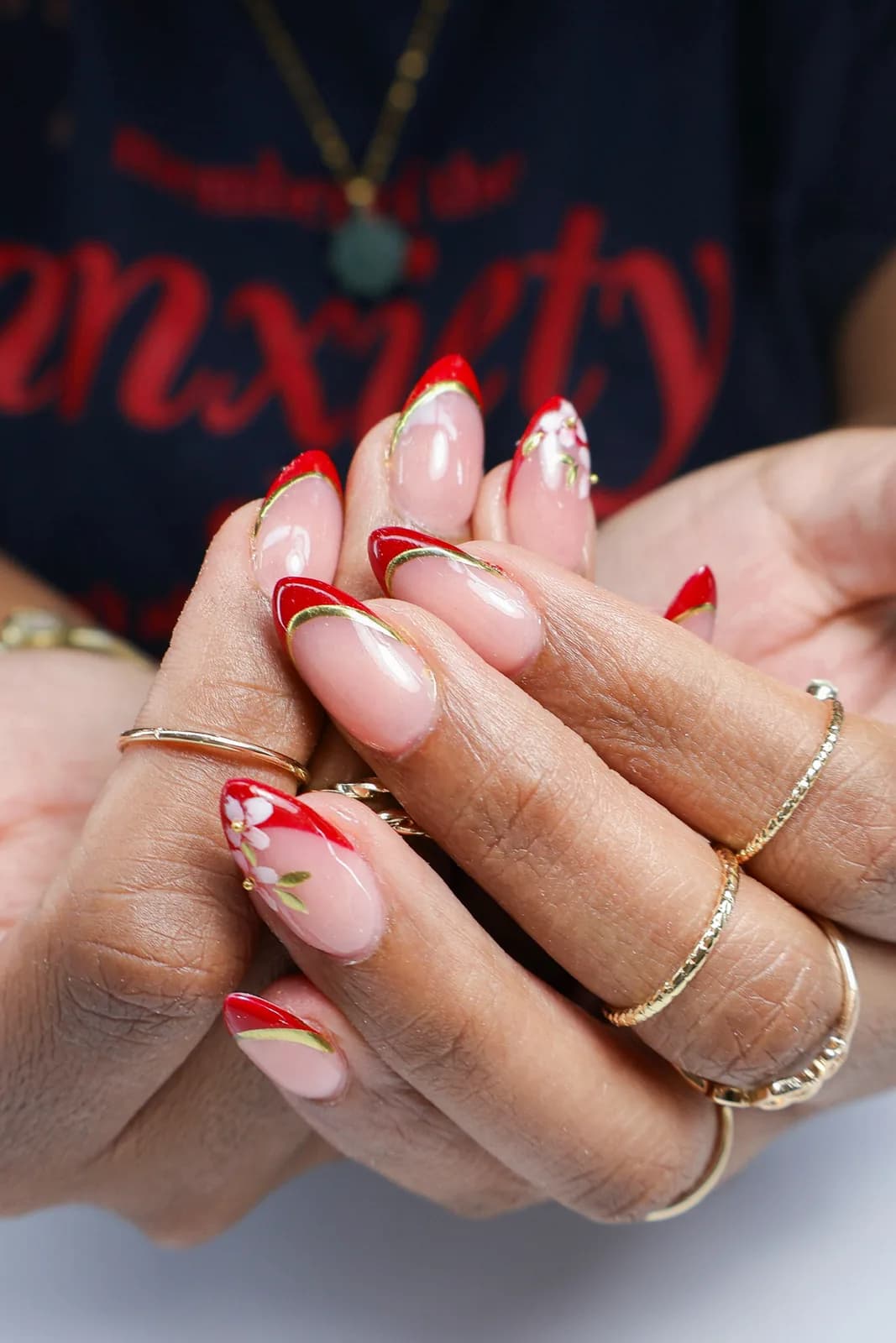 Red French tip nails with white flowers and gold leaf details
