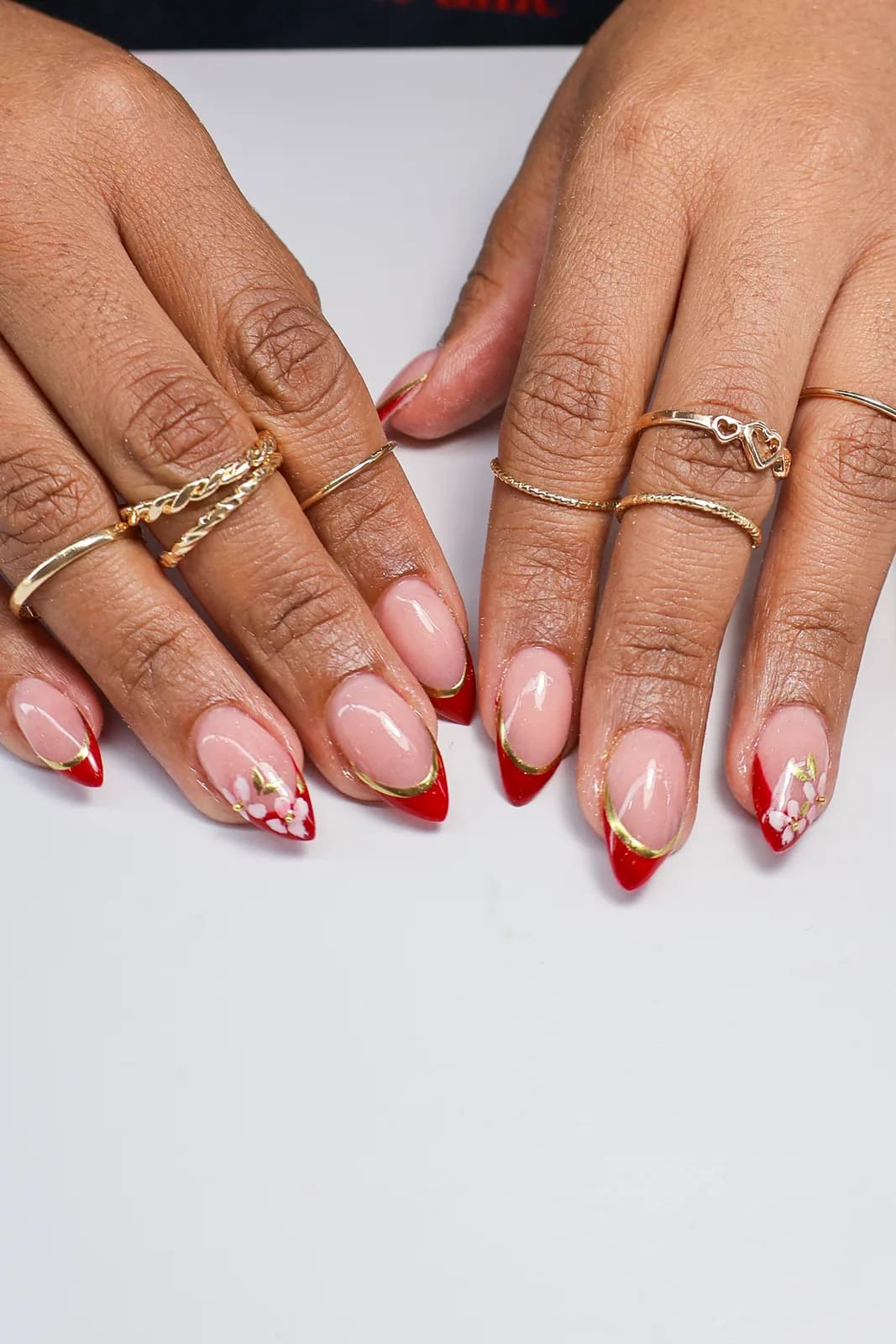 Red micro French manicure with fine gold outlines on natural-length nails