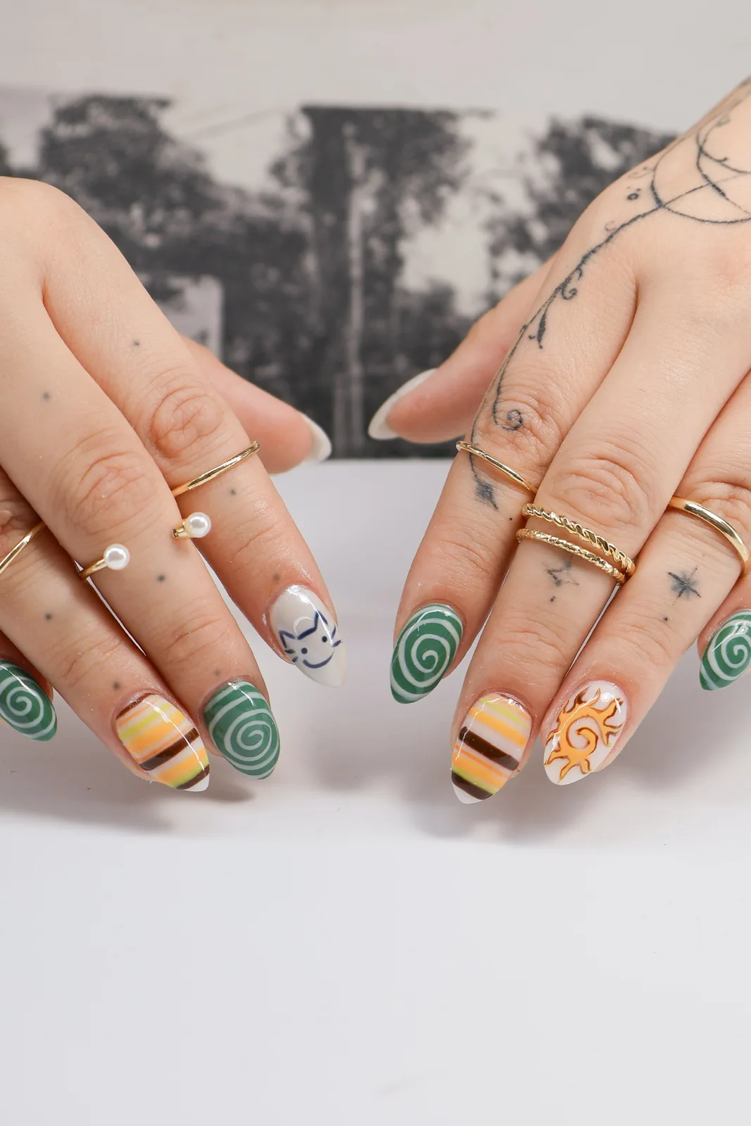 Both hands showing seventies-inspired swirl and stripe almond nail art