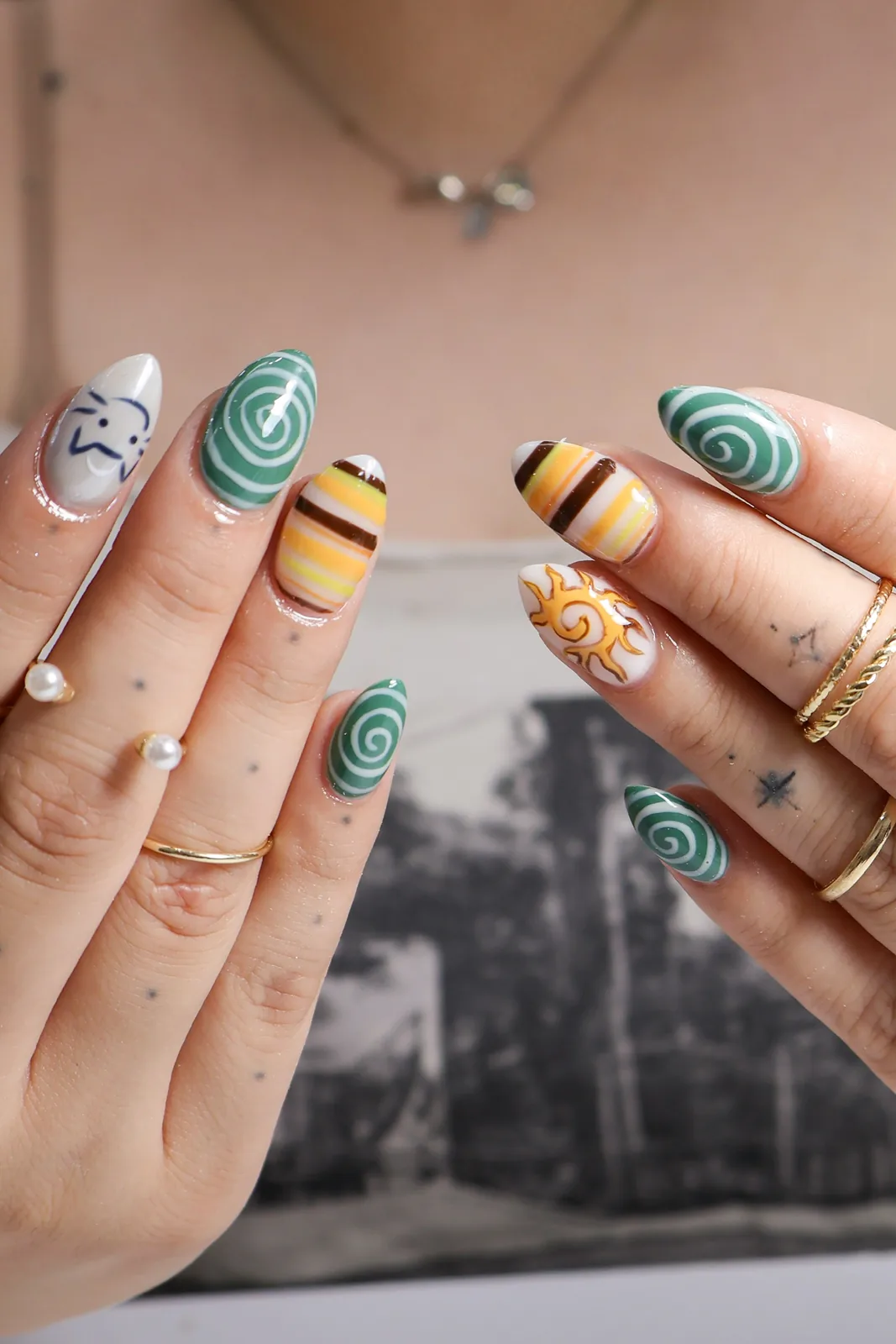 Retro almond nail art with green swirls, warm stripes, and a smiling sun