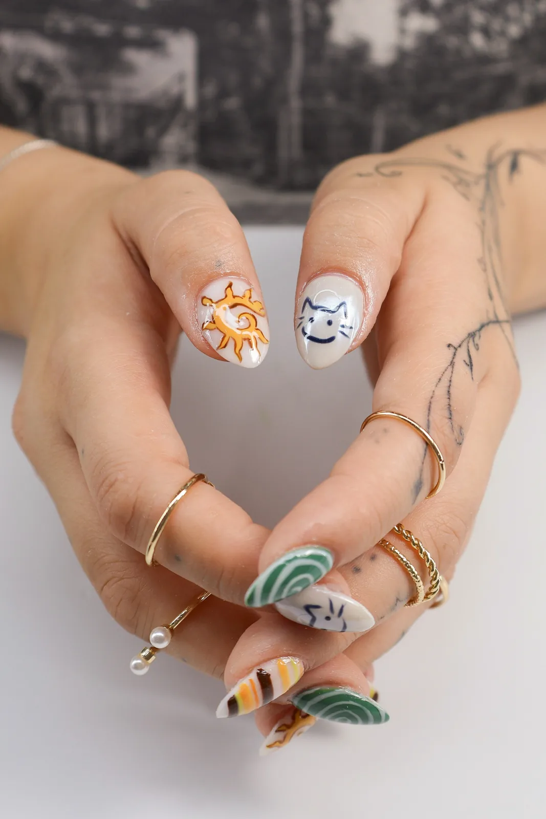 Close-up of hand-painted sun and cat face nail art on almond nails