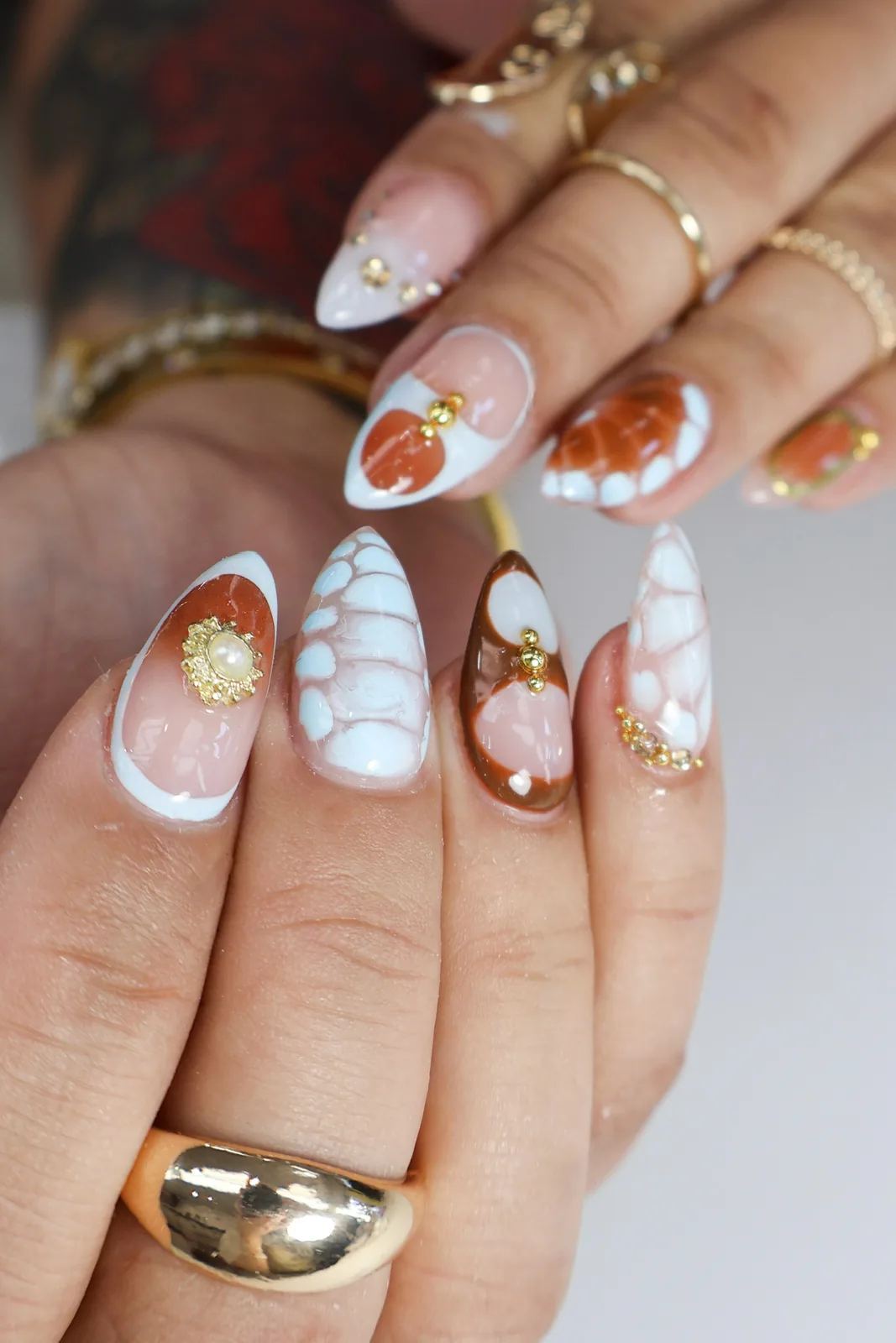 Close-up of almond nails with white crocodile texture and amber tortoiseshell French tips