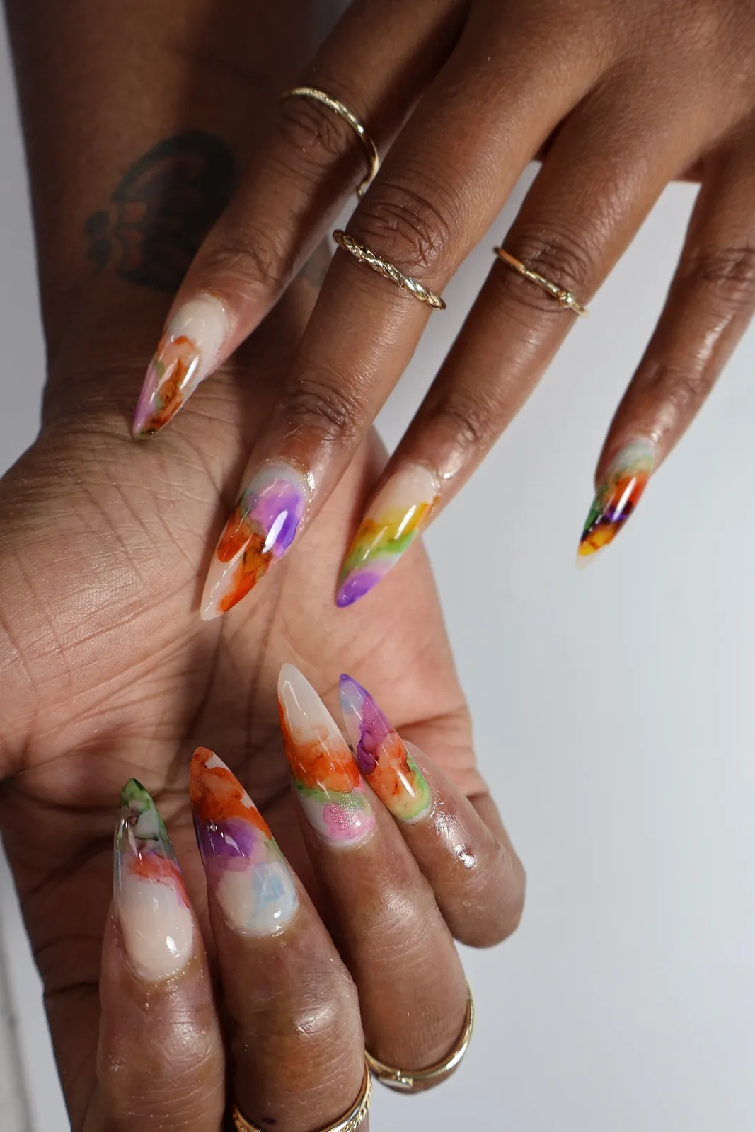 Palms-up view of long watercolor stiletto nails with marbled color