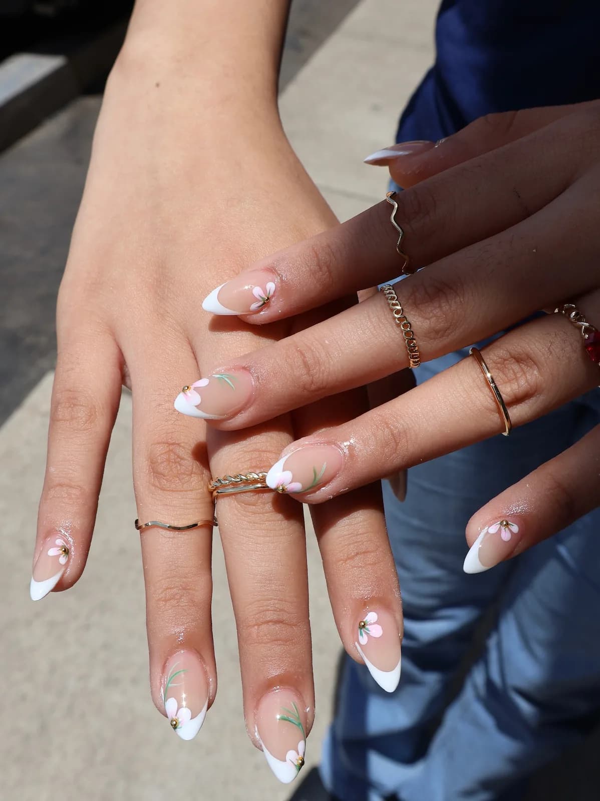 White French tip nails with dainty flower accents in natural sunlight